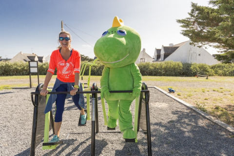 Vrouw en iemand in een groen dinosauruspak sporten samen bij Flower Camping Les Paludiers, Frankrijk.