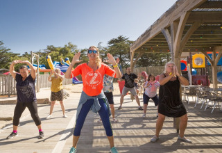 Des adultes suivent un cours de fitness en plein air et ensoleillé au Flower Camping Les Paludiers, France.