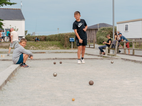 Zwei Jungen spielen Boule auf einem Schotterplatz im Flower Camping Les Paludiers in Pays de la Loire, Frankreich.