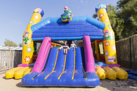 Zwei Kinder spielen auf einer bunten Hüpfburg-Rutsche bei Flower Camping Les Paludiers in Pays de la Loire.