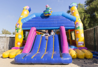 Two children play on a colorful inflatable slide at Flower Camping Les Paludiers in Pays de la Loire, France.