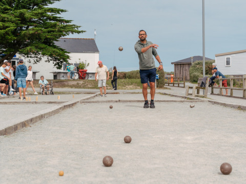Persone che giocano a pétanque su un campo di ghiaia a Flower Camping Les Paludiers in Pays de la Loire, Francia.