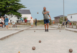 Des personnes jouent à la pétanque sur un terrain de gravier au Flower Camping Les Paludiers, Pays de la Loire.