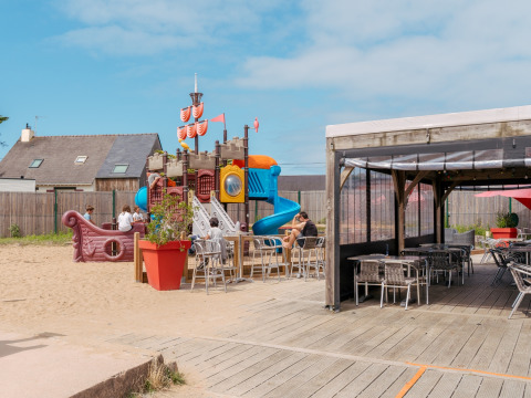 Spielplatz mit Piratenschiff und Sitzbereich im Flower Camping Les Paludiers in Pays de la Loire, Frankreich.