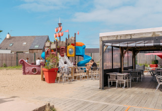 Spielplatz mit Piratenschiff und Sitzbereich im Flower Camping Les Paludiers in Pays de la Loire, Frankreich.
