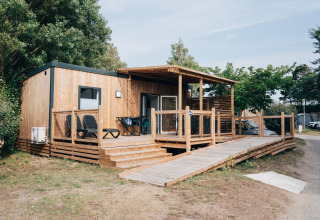 Cabaña de madera con gran terraza y rampa en Flower Camping Les Paludiers, Pays de la Loire, Francia.