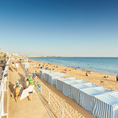 Strandzicht aan Flower Camping Les Paludiers in Pays de la Loire, Frankrijk, met badhokjes en vakantiegangers.