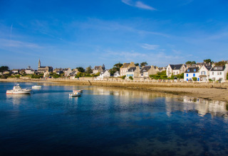 Vue côtière du Flower Camping Les Paludiers, village vacances en Pays de la Loire, France, avec bateaux et maisons.