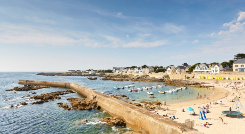 Playa y casas de vacaciones en Flower Camping Les Paludiers, Pays de la Loire, Francia, con barcos en la bahía.
