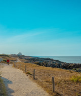 Kustwandeling nabij Batz-sur-Mer, Pays de la Loire, met charmante huizen, rotsen en blauwe hemel.