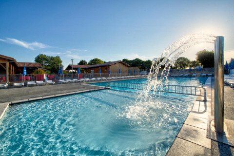 Piscina al aire libre con fuente de agua y tumbonas en Flower Camping Le Bel Air, Nouvelle-Aquitaine, Francia.