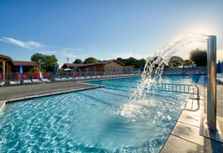 Piscina all'aperto con getto d'acqua e lettini a Flower Camping Le Bel Air, Nouvelle-Aquitaine, Francia.