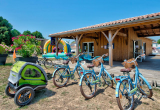 Fahrräder mit Kinderanhänger vor der Rezeption des Flower Camping Le Bel Air in Nouvelle-Aquitaine, Frankreich.