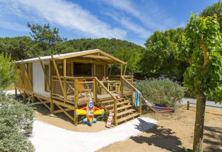 Campinghytte i træ med legetøj på terrassen og hængekøje, set i Flower Camping Le Bel Air, Nouvelle-Aquitaine.