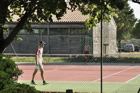 Zwei Personen spielen Tennis auf einem Außenplatz im Flower Camping Le Bel Air, Nouvelle-Aquitaine, Frankreich.