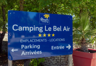 Skilt ved Flower Camping Le Bel Air i Nouvelle-Aquitaine, Frankrig, med oplysninger om parkering og indgang.