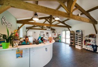 Recepción de Flower Camping Le Bel Air en Nouvelle-Aquitaine, Francia, con personal y tienda de recuerdos.