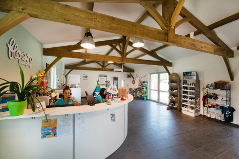 Recepción de Flower Camping Le Bel Air en Nouvelle-Aquitaine, Francia, con personal y tienda de recuerdos.