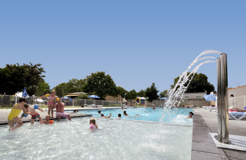 Bambini e famiglie giocano in piscina al Flower Camping Le Bel Air, un villaggio vacanze in Nouvelle-Aquitaine, Francia.