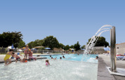 Families and children play in a swimming pool at Flower Camping Le Bel Air holiday park in Nouvelle-Aquitaine, France.