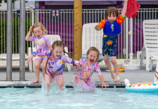 Børn hopper glade i en swimmingpool på Flower Camping Le Bel Air i Nouvelle-Aquitaine, Frankrig.