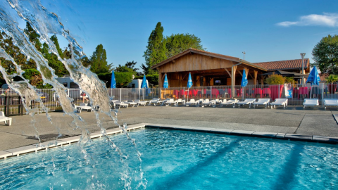 Piscina y tumbonas en el parque de vacaciones Flower Camping Le Bel Air en Nouvelle-Aquitaine, Francia en un día soleado.