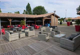 Area relax all'aperto con arredi moderni e ombrelloni al Flower Camping Le Bel Air, Nouvelle-Aquitaine, Francia.