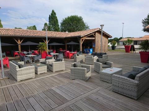 Area relax all'aperto con arredi moderni e ombrelloni al Flower Camping Le Bel Air, Nouvelle-Aquitaine, Francia.