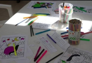 Crayons de couleur et coloriages éparpillés sur une table au Flower Camping Le Bel Air, Nouvelle-Aquitaine, France.