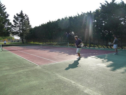 Menschen spielen Tennis auf einem Außenplatz bei Flower Camping Le Bel Air in Nouvelle-Aquitaine, Frankreich.