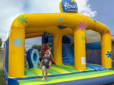 Kinderen amuseren zich op een kleurrijk springkasteel bij Flower Camping Le Bel Air, Nouvelle-Aquitaine, Frankrijk.