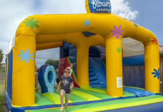 Bambini giocano felici su un colorato castello gonfiabile al Flower Camping Le Bel Air, Nouvelle-Aquitaine, Francia.