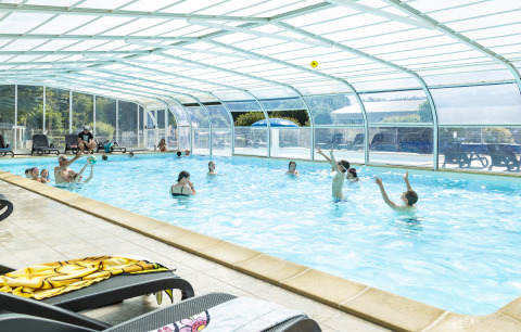 Covered swimming pool with families and children enjoying their holiday at Flower Camping Le Kerleyou in Brittany.