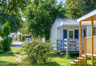 Mobile home and green surroundings at Flower Camping Le Kerleyou holiday park in Brittany, France, on a sunny day.