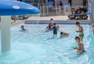 Bambini giocano nella piscina per bambini con fungo d'acqua al Flower Camping Le Kerleyou in Bretagna, Francia.