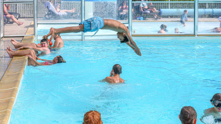 Kinderen en volwassenen genieten van het overdekte zwembad bij Flower Camping Le Kerleyou in Bretagne, Frankrijk.