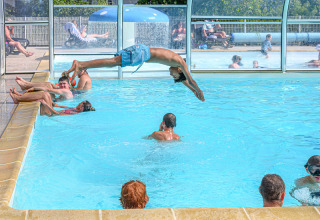 Bambini e adulti si divertono nella piscina coperta di Flower Camping Le Kerleyou in Bretagna, Francia.
