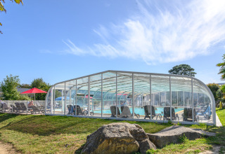 Udendørs swimmingpool med gennemsigtigt tag på Flower Camping Le Kerleyou feriepark i Bretagne, Frankrig.
