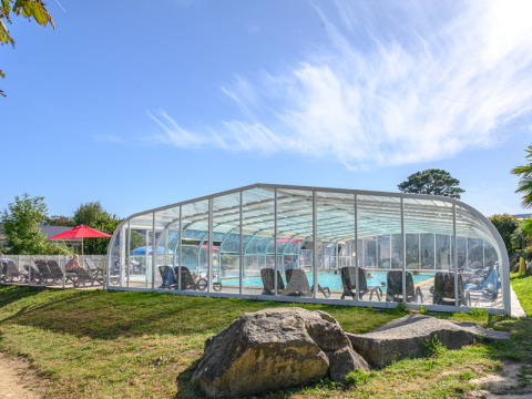 Outdoor swimming pool with a transparent roof at Flower Camping Le Kerleyou holiday park in Brittany, France.