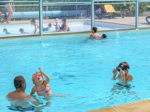 Famiglie si divertono in piscina coperta al Flower Camping Le Kerleyou, un villaggio vacanze in Bretagna, Francia.