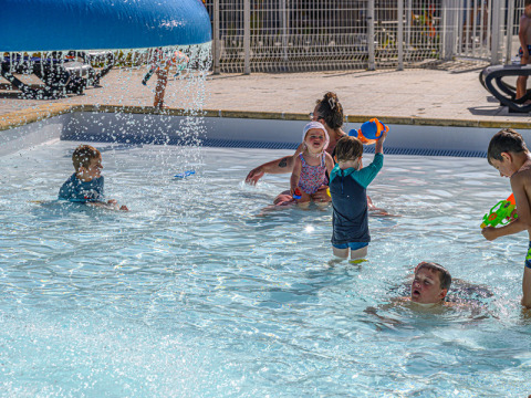 Kinderen spelen en spetteren in het kinderbad bij Flower Camping Le Kerleyou vakantiepark in Bretagne, Frankrijk.