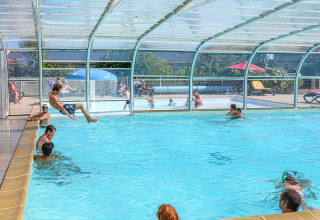 Piscina coperta al Flower Camping Le Kerleyou, persone che si divertono nell'acqua in un villaggio vacanze in Bretagna.