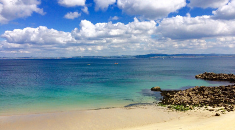 Impresionante vista de playa de arena y mar azul en Flower Camping Le Kerleyou en Bretaña, Francia.