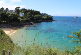 Beautiful coastal view at Flower Camping Le Kerleyou, Brittany, France, with blue sea and lush greenery.