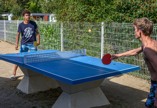 To unge mænd spiller bordtennis udendørs på Flower Camping Le Kerleyou, en feriepark i Bretagne, Frankrig.
