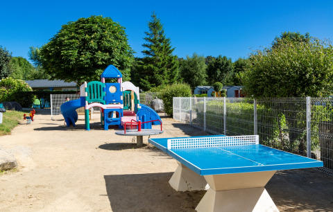 Speeltuin en blauwe tafeltennistafel bij Flower Camping Le Kerleyou in Bretagne, Frankrijk op een zonnige dag.