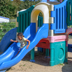 Een kind speelt op een blauwe glijbaan op de speeltuin van Flower Camping Le Kerleyou in Bretagne, Frankrijk.