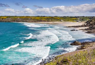 Kystlandskab med bølger og sandstrand nær Flower Camping Le Kerleyou-holiday park i Bretagne, Frankrig