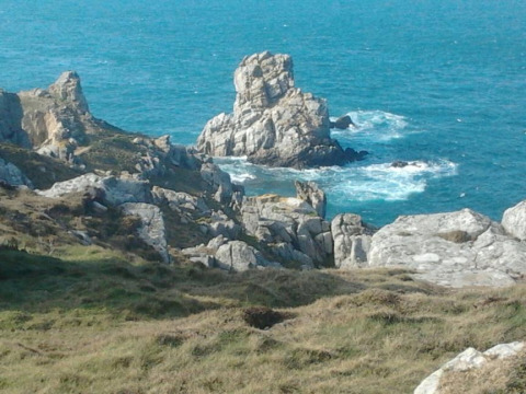 Rocky coastline and cliffs with ocean waves at Flower Camping Le Kerleyou in Brittany, France.