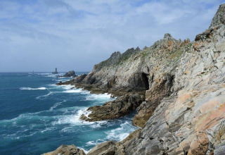 Rotsachtige kustlijn met blauwe zee en golven bij Flower Camping Le Kerleyou in Bretagne, Frankrijk.